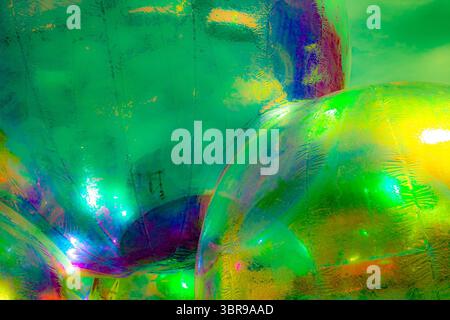 A vibrant, abstract artwork featuring a close-up of a shiny, surface reflecting multicolored light. The dominant hues are red, orange, yellow, and pin Stock Photo
