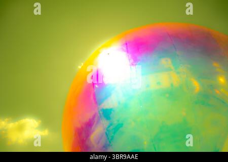 A vibrant, abstract artwork featuring a close-up of a shiny, surface reflecting multicolored light. The dominant hues are red, orange, yellow, and pin Stock Photo