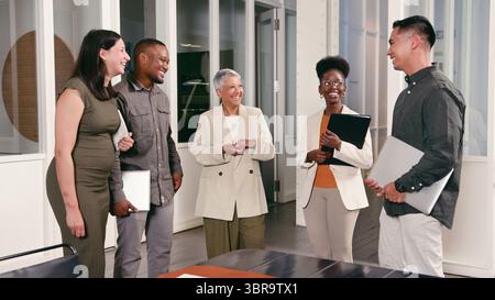 Professional Team Engaging in Friendly Discussion in a Modern Office Environment Stock Photo
