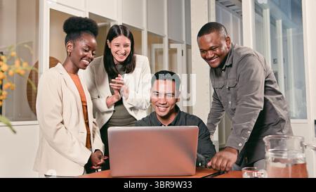Group of Colleagues Collaborating on a Laptop in a Modern Office Setting Stock Photo