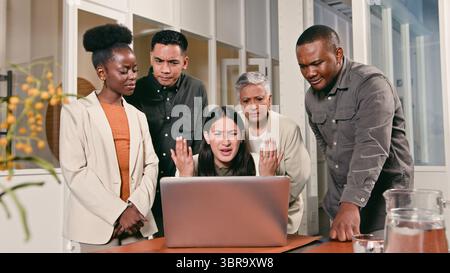 Team of Colleagues Expressing Concern Around a Laptop in a Modern Office Setting Stock Photo