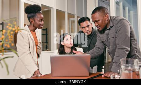 Business Team Collaborating in Office with Focus on Discussion Around Laptop Stock Photo