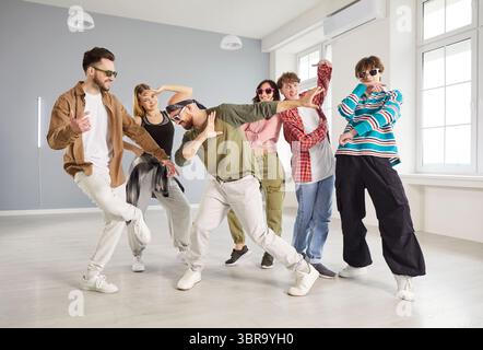 Group of trendy young people dancing in studio, performing hip hop moves and expressing energy. Stock Photo