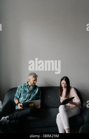 Two colleagues discussing work while sitting together on a sofa Stock Photo
