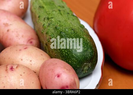 Colorful assortment of garden vegetables on a wooden table in soft light. Stock Photo