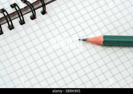 A blank grid notebook lies open beside a sharpened pencil, inviting ideas and sketches. Stock Photo