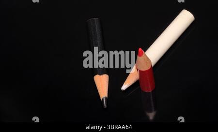 Three colored pencils rest on a reflective black surface, showcasing their vibrant hues. Stock Photo