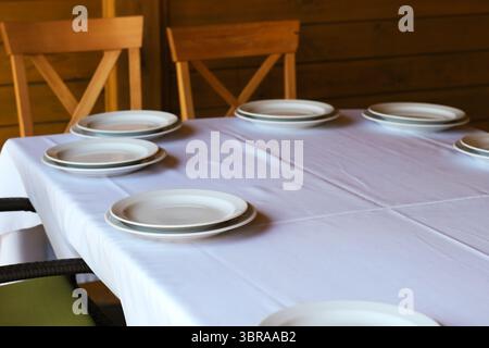 Elegant table set with white plates, ready for a warm gathering with loved ones. Stock Photo