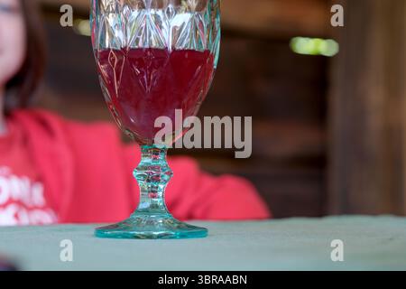A beautiful glass filled with a vibrant drink sits on a table in warm surroundings. Stock Photo
