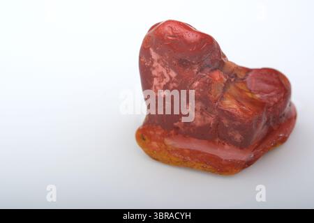 A striking red mineral sits on a smooth surface, revealing intricate natural patterns. Stock Photo
