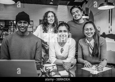 diverse group of young professionals smiling at camera in a modern coworking space. Collaborative multicultural team working on creative project. Blac Stock Photo