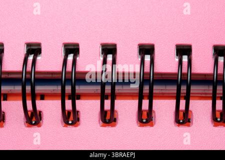 A spiral notebook lies open on a vibrant pink surface, ready for ideas. Stock Photo