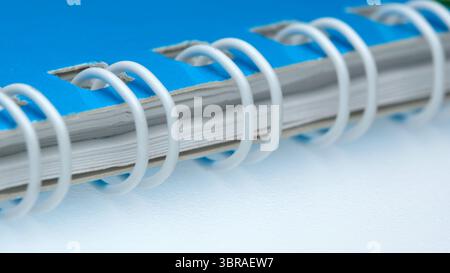 Blue spiral notebook lays open on a clean white surface, ready for notes. Stock Photo