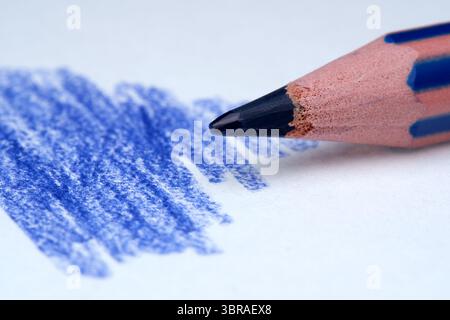 A close-up view of a blue pencil making vibrant strokes on paper. Stock Photo