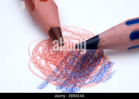 Two crayons blend vibrant shades on paper, creating a colorful swirl of hues. Stock Photo