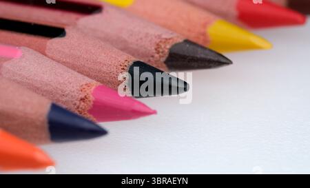 Vibrant colored pencils line up in perfect order on a white surface. Stock Photo