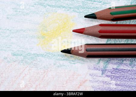 Three colorful pencils rest on a textured canvas, ready to draw. Stock Photo