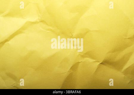 Soft light reveals fine wrinkles on vibrant yellow paper's surface. Stock Photo
