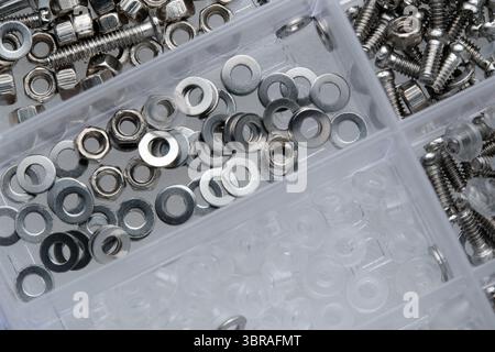 Metal washers, screws, and plastic spacers are arranged in trays. Stock Photo
