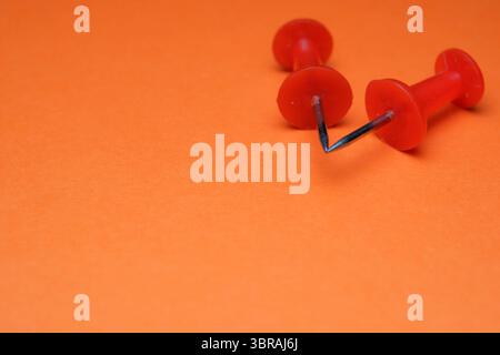 Colorful thumbtacks arranged playfully on an orange surface evoke creativity. Stock Photo