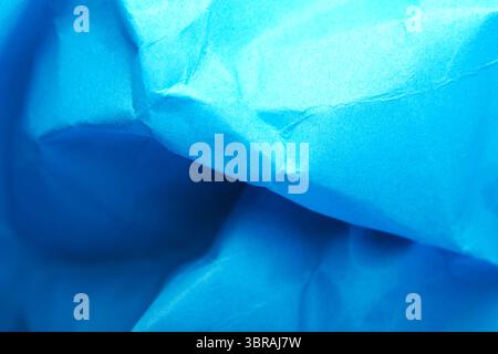 Close-up of crumpled blue paper highlights captivating light play. Stock Photo