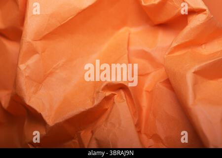 Vibrant orange wrapping paper crumples and folds, creating an artistic backdrop. Stock Photo