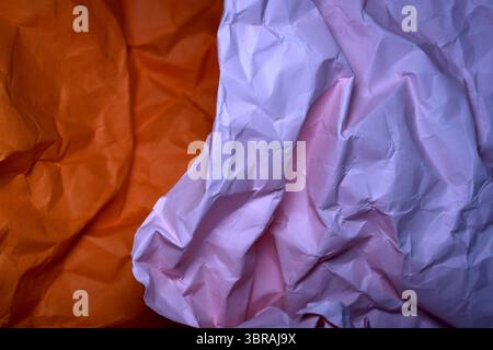 Crumpled paper in shades of orange and pink creates a textured abstract artwork. Stock Photo