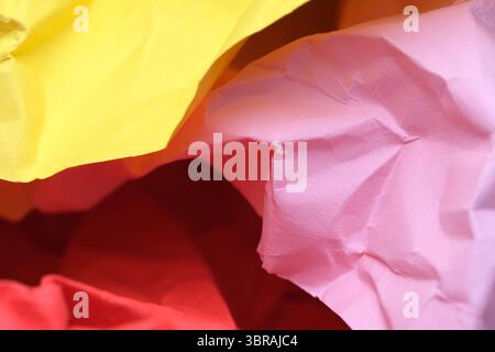 Crumpled paper in vibrant yellow, pink, and red contrasts beautifully. Stock Photo