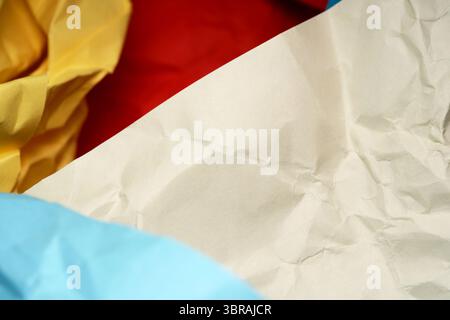 Crinkled colorful papers lay intertwined, forming an artistic abstract display. Stock Photo