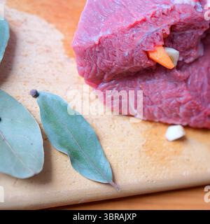 Slicing tender meat with aromatic bay leaves and spices laid out. Stock Photo