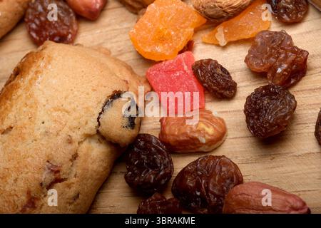 Colorful dried fruits and cookies are artfully scattered on wood. Stock Photo