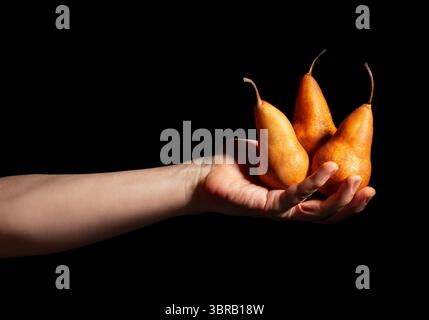pears in hand on black background Stock Photo