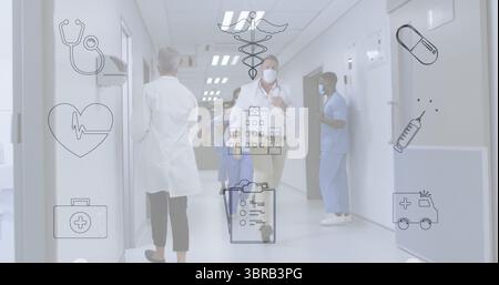 Running doctor wearing white lab coat mask badge in hospital corridor with nurses in blue scrubs Stock Photo