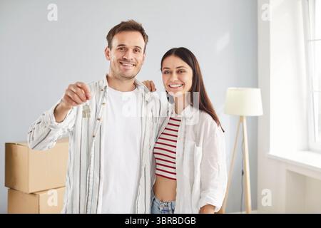 Smiling happy young family, spouses standing in living room keys holding, celebrate relocation day  Stock Photo