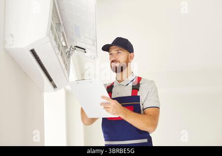 Young professional electrician man or technician maintaining air conditioner in new apartment. Stock Photo
