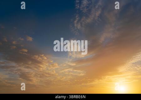 Glowing real sky and sun at sunset texture background overlay. Dramatic red, orange, and purple clouds. High resolution photography perfect for sky re Stock Photo