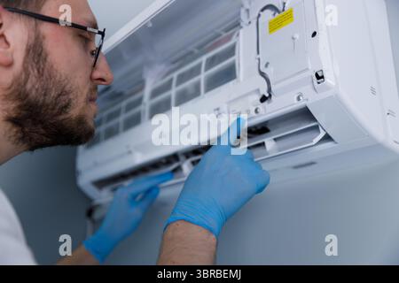 Professional Technician Performing Maintenance on Air Conditioning Unit to Ensure Optimal Functionality and Air Quality Inside Residences and Offices Stock Photo