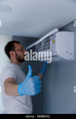 Professional Technician Giving Thumbs Up After Successfully Installing Air Conditioning Unit in Modern Indoor Setting, Showcasing Commitment to Stock Photo