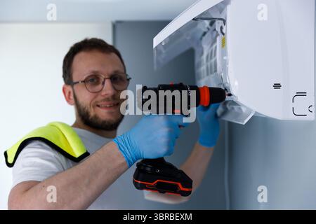 A Skilled Technician Installing an Air Conditioning Unit Using a Cordless Drill, Ensuring Efficient Cooling Solutions for Modern Spaces with Stock Photo