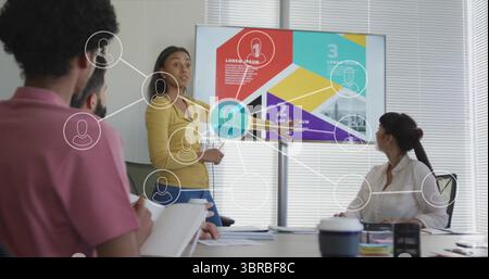 Woman wearing mustard blouse holding remote presenting infographic display in meeting room Stock Photo