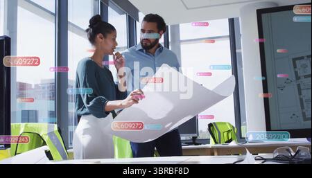 Examining architects in teal blouse and blue shirt studying blueprint in office, with data tags Stock Photo