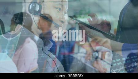 Asian man wearing headset and shirt talking in office call center, with stylus pointing at tablet Stock Photo