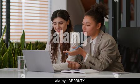 Multiracial girls African American Caucasian business women female friendly smiling colleagues multiethnic businesswomen partners online meet laptop Stock Photo