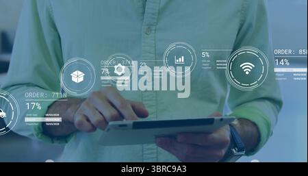 Man wearing green shirt tapping tablet in office with order tracking icons, IDs and percentages Stock Photo