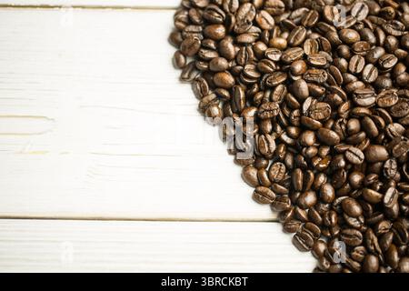 Mound of roasted coffee beans is being shown in flat design on white-painted wood plank surface Stock Photo
