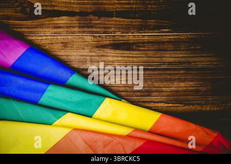 Flat design draping folded rainbow-striped flag on wood planks creating vivid contrast, copy space Stock Photo