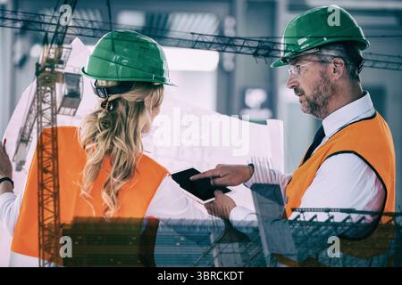Male and female engineers discussing over blueprint and digital tablet Stock Photo