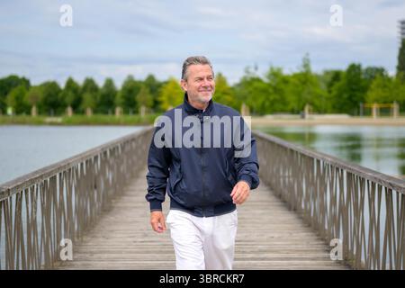 Confident senior man walking across a wooden bridge on a pleasant day. Stock Photo