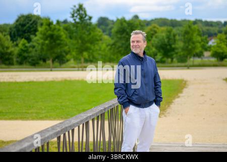 Portrait of a mature man standing with hands in pockets on a wooden bridge in a park. Stock Photo