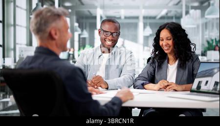 Professional Realtor Assists Diverse Couple With House Leasing Consultation Stock Photo